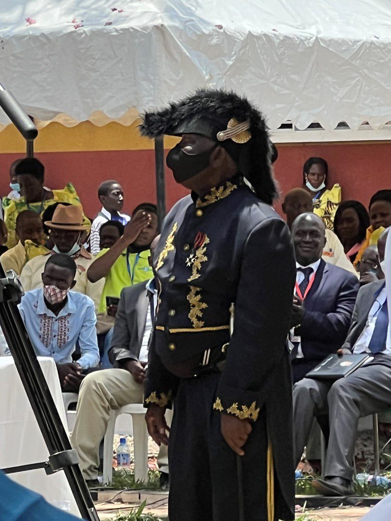 Masked person in black-and-gold ceremonial uniform