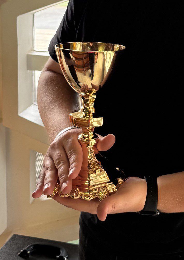 Person holding ornate gold chalice