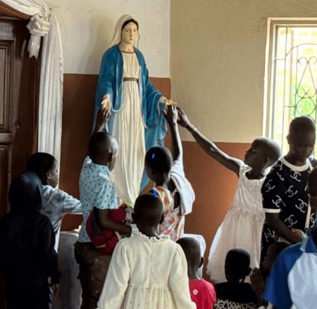 Children touching Virgin Mary statue in church